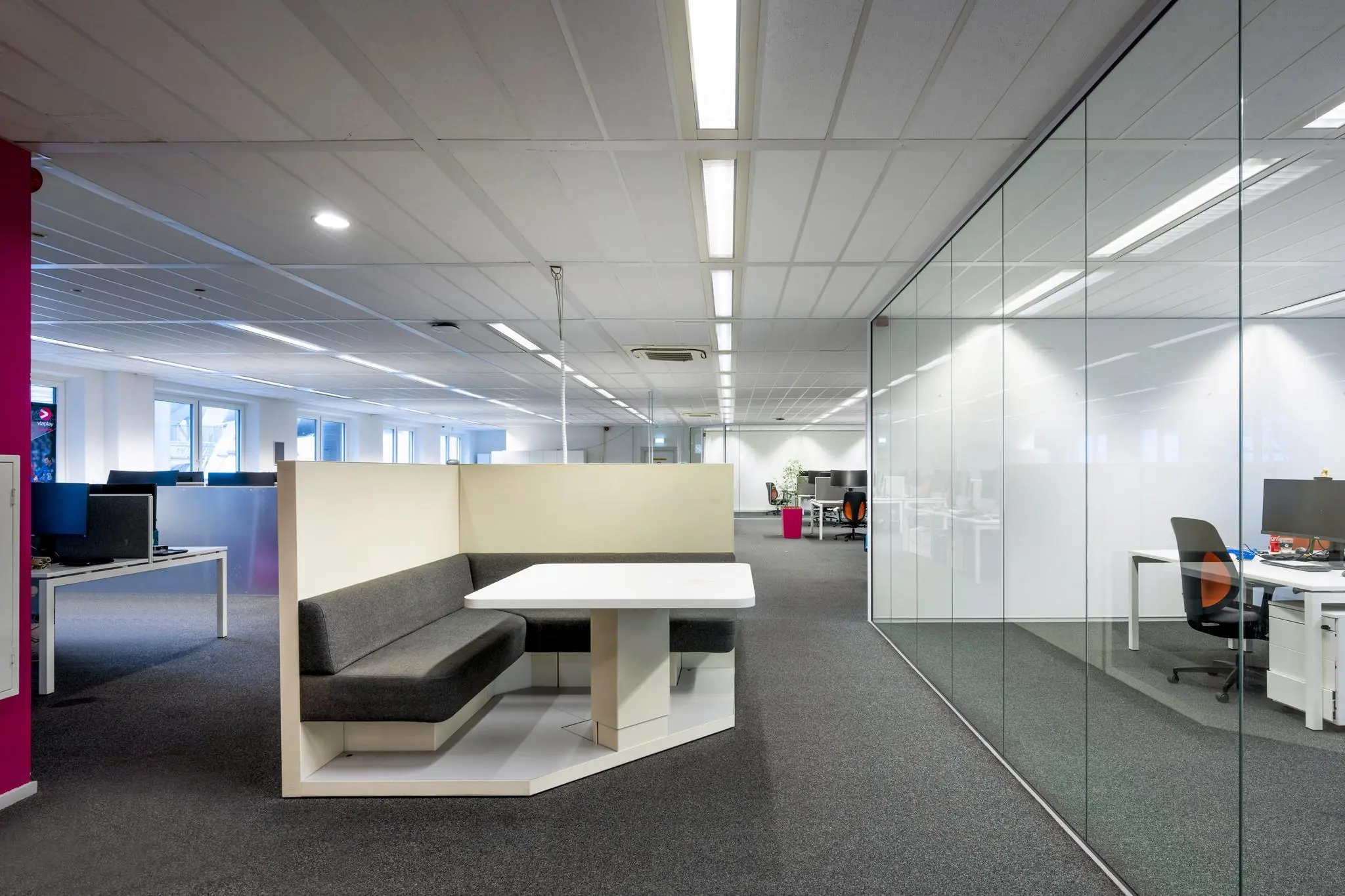 Modern kantoorinterieur aan de Johan Cruijff Boulevard met open werkplekken, glazen wanden en een zithoek met vergadertafel.